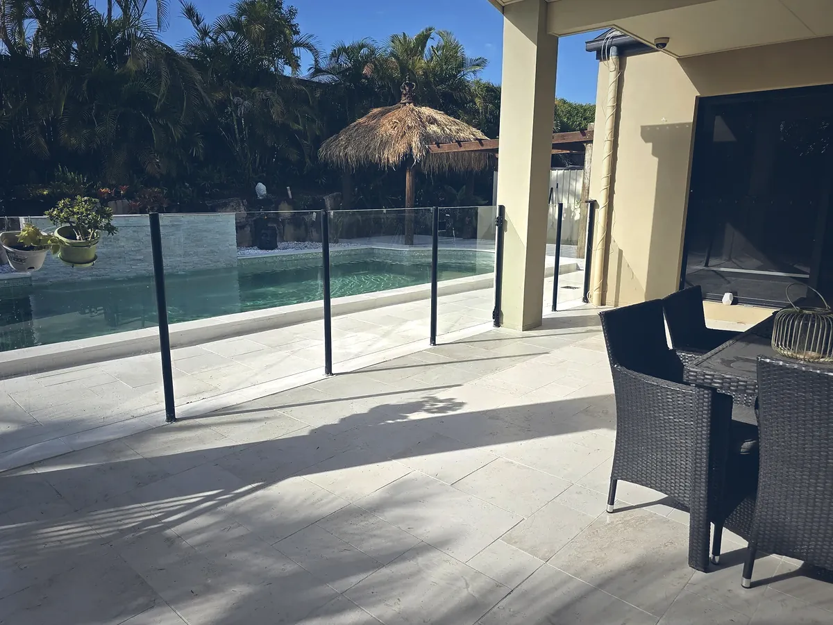 Travertine pool surround with frameless glass fencing and outdoor dining
